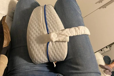 Knee pillow between the knees with its strap around one leg.